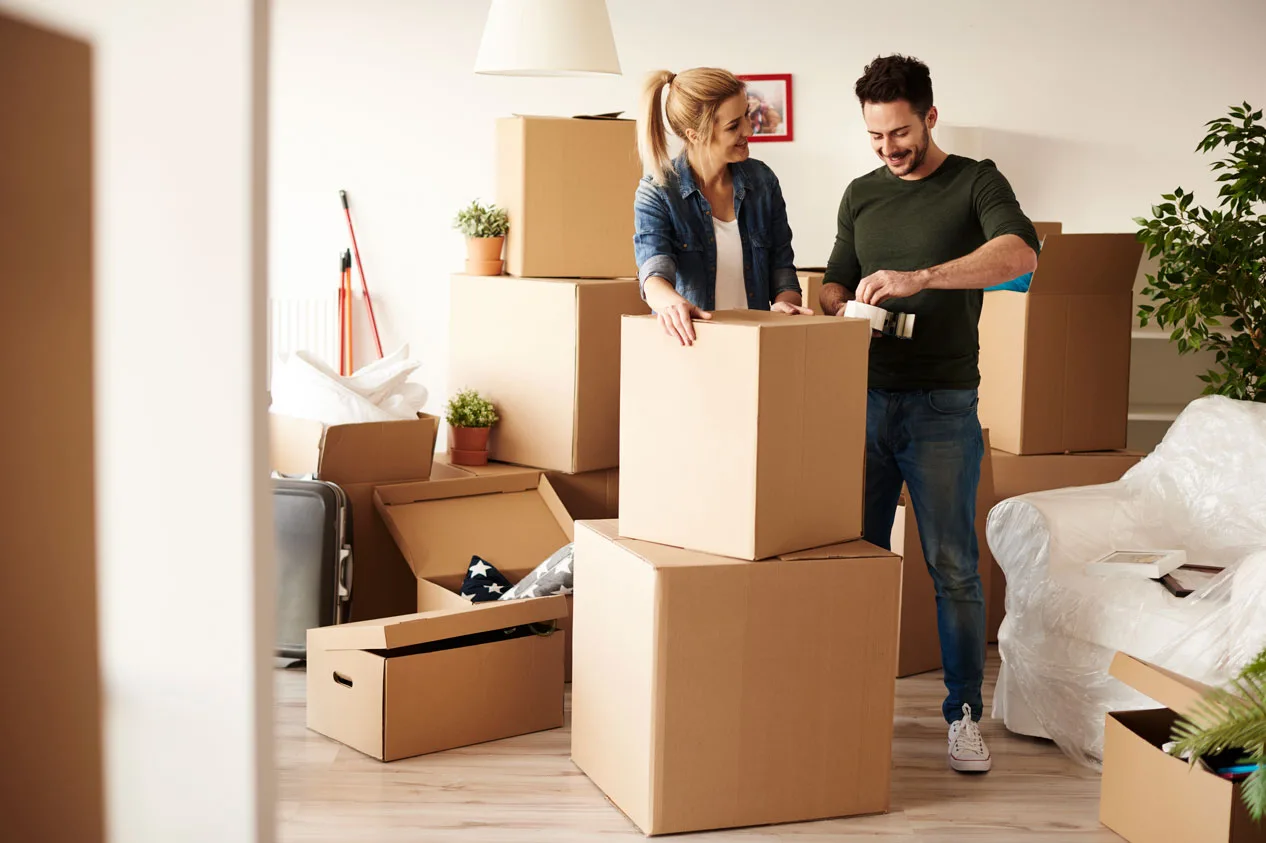 a man and woman standing in a room with boxes